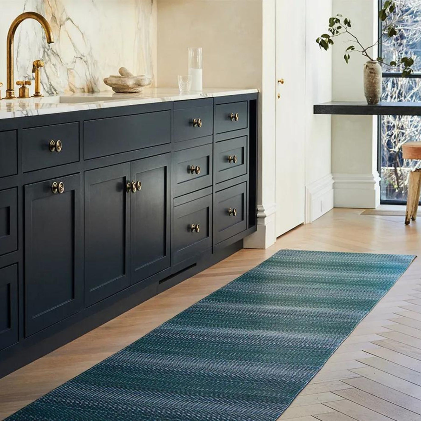 Chilewich Quill Floormat in Kitchen with Herringbone Floors Black Cabinets Marble Backsplash