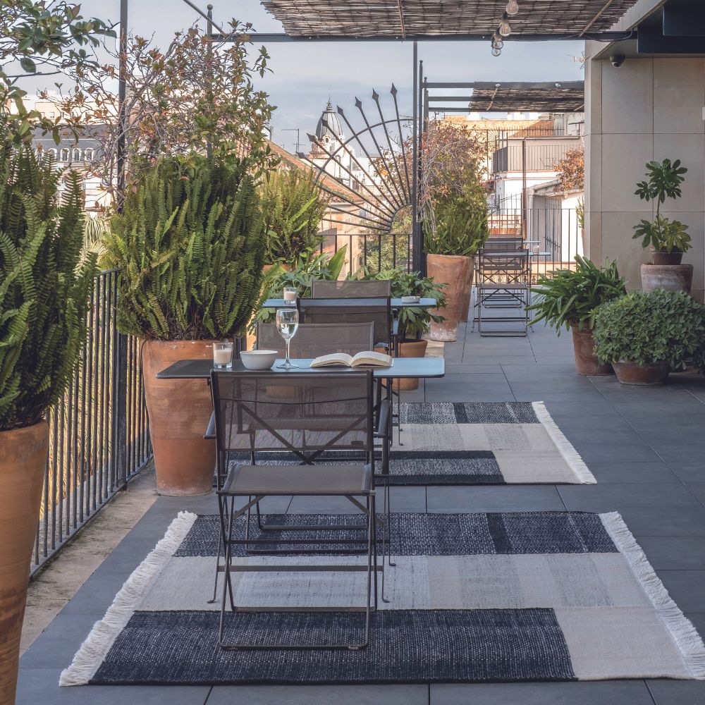 nanimarquina Tres Outdoor Rugs on Patio with Cafe Tables