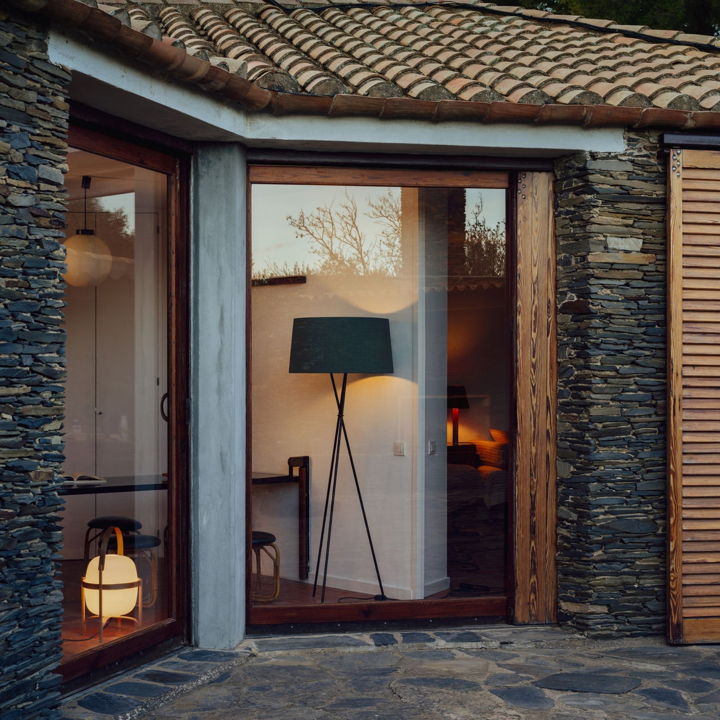 Santa Cole Tripode Floor Lamp and Cesta Table Lamp in Barcelona Stone House Lit Up in Window