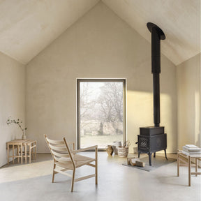 Carl Hansen Wegner CH53 Foot Stool by Hans Wegner in room with CH44 Ladderback Chair, Nesting Tables, and Wood Stove