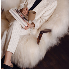 Eikund Fluffy Lounge Chair Natural White Sheepskin in Loft with Woman Reading and Drinking Coffee