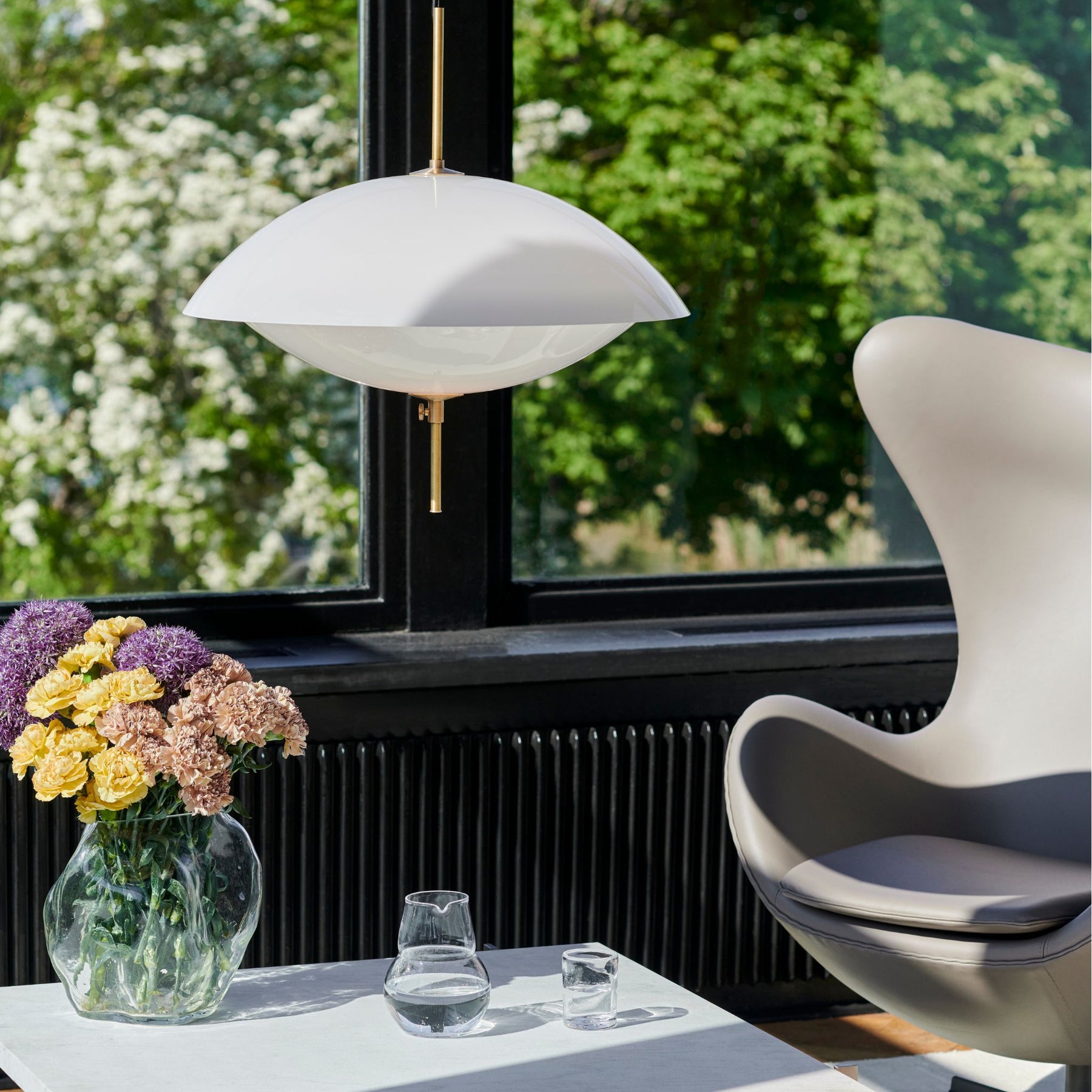 Fritz Hansen Clam Pendant by Window Over Coffee Table with Flowers and Grey Leather Egg Chair