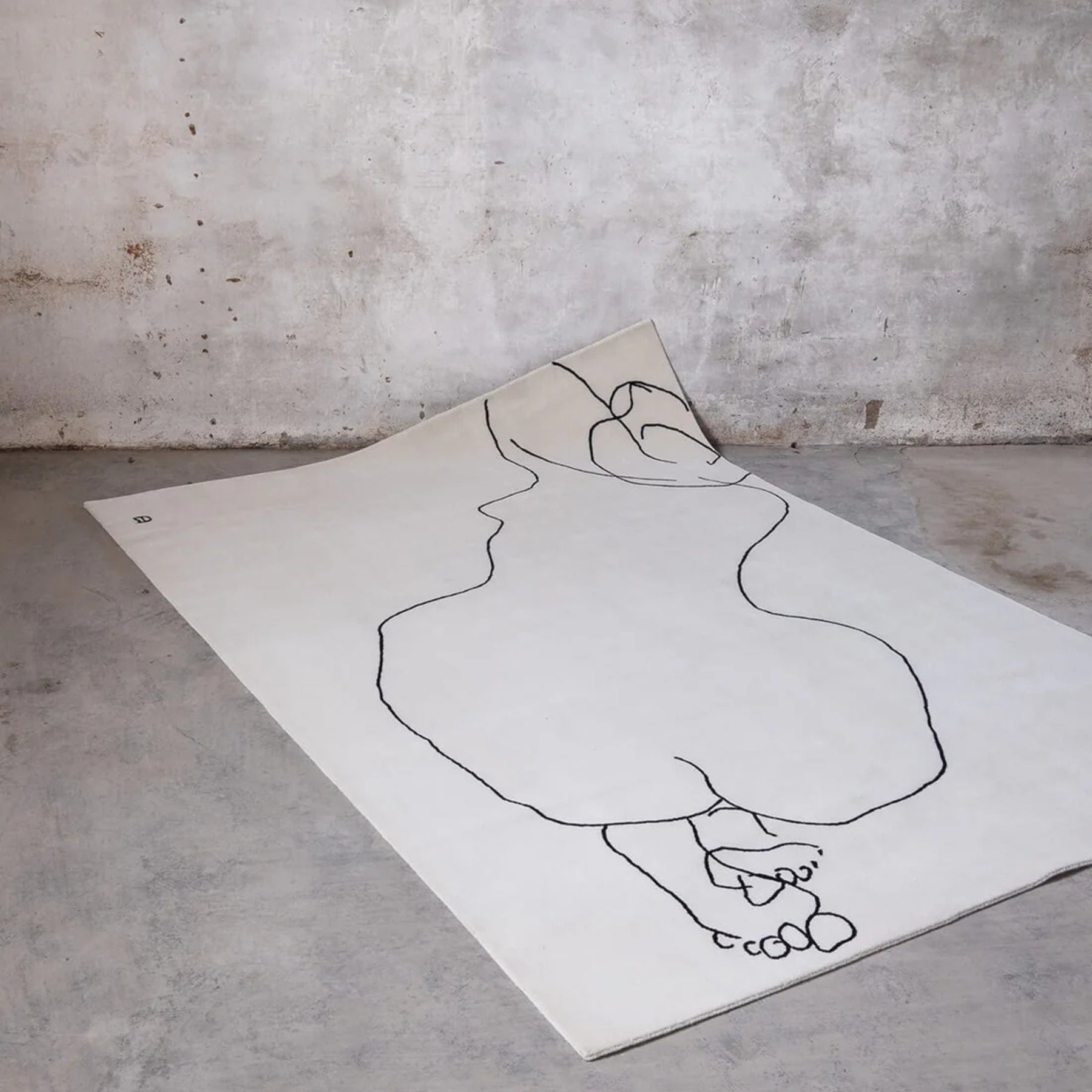 nanimarquina chillida figura humana rug in room with concrete floor