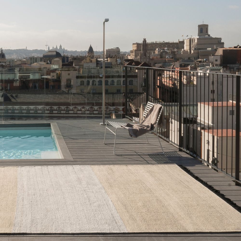 Nanimarquina Tres Stripes Outdoor Rug by Pool with Barcelona Cityscape
