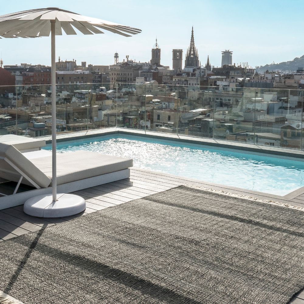 nanimarquina Tres Texture Outdoor Rug Black by Pool with Barcelona Cityscape
