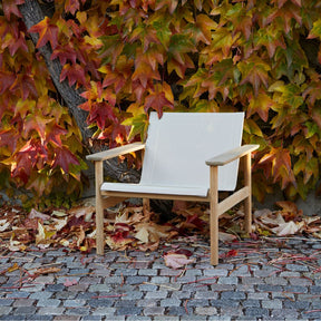 Pelagus Lounge Chair Teak and Mesh Angled on Cobblestone Terrace with Fall Leaves