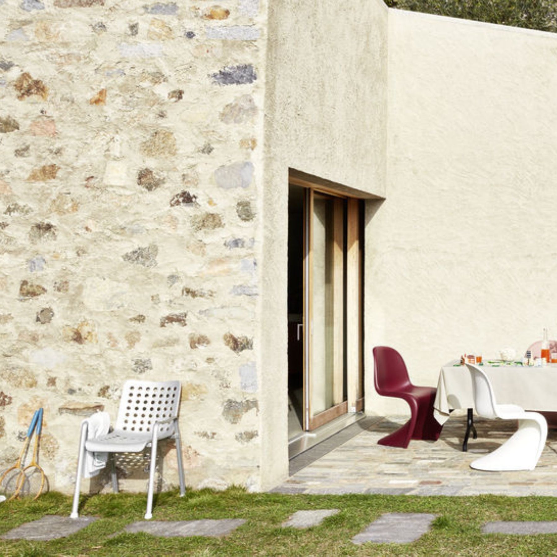 Vitra Landi Chair by Hans Coray Outdoors with Stone Wall and Panton Chairs