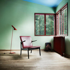 Ole Wanscher Beak Chair in red leather with black oak frame  in room with red Louis Poulsen floor lamp.