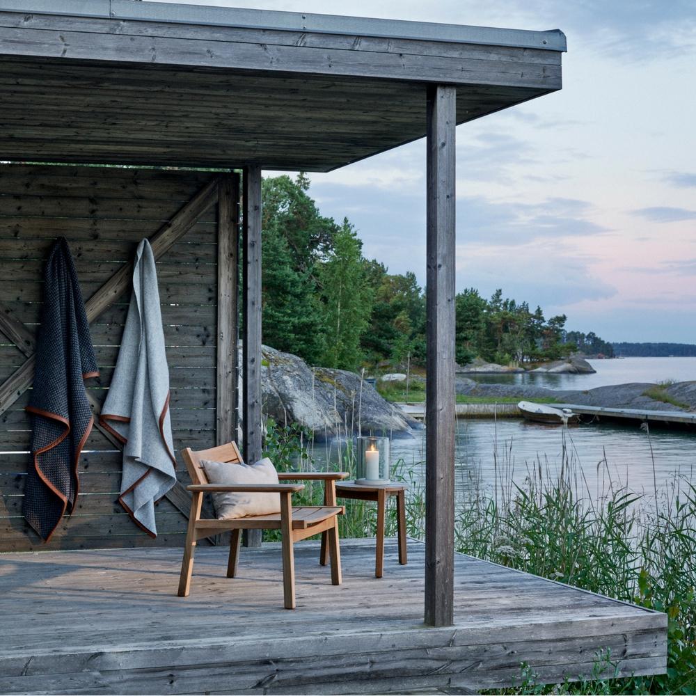 Djuro Teak Lounge Chair with Djuro Small Lounge Table, Marstrand Candle Lantern, and Haverdal and Morup Throws by Skargaarden