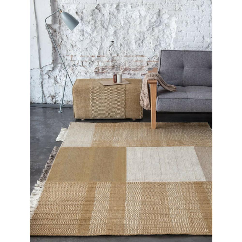 Nani Marquina Tres Rug Ochre in room with Pouf