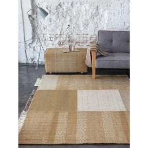 Nani Marquina Tres Rug Ochre in room with Pouf