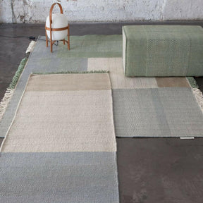 Nani Marquina Tres Rugs layered in room with Pouf