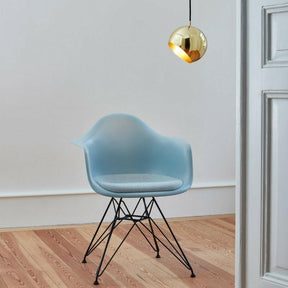 Nyta Tilt Globe Pendant Brass in room with Eames Eiffel Chair