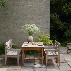 Skagerak Drachmann Dining Table Bench Chairs Outside Brick Home with Flowers